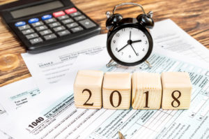 Wooden cubes with numbers "2018" with tax forms and calculator on the table. Business concept. Pay tax in 2018 year.