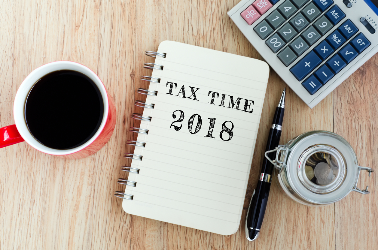 Tax Time text on notepad - coffee, jar coins, pen and calculator on top of wooden table. 2018 Year-End Tax Strategies