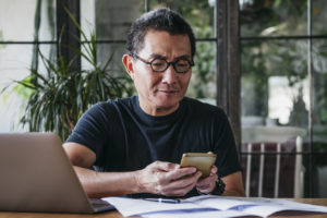 Man working remotely using mobile phone to make business payments.