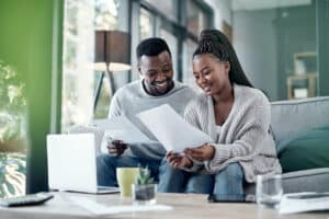 Happy couple at home planning for their financial goals - setting up plans for better budgeting.