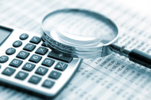 Business audits concept - Financial records on a table with a calculator and magnifying glass.