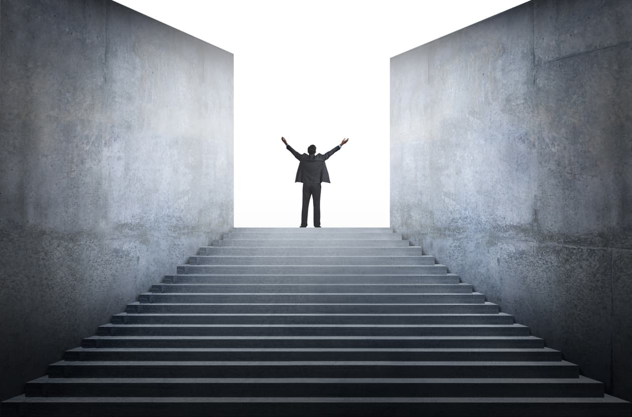 Successful entrepreneurs concept - Businessman standing on top of a flight of stairs with his arms raised.